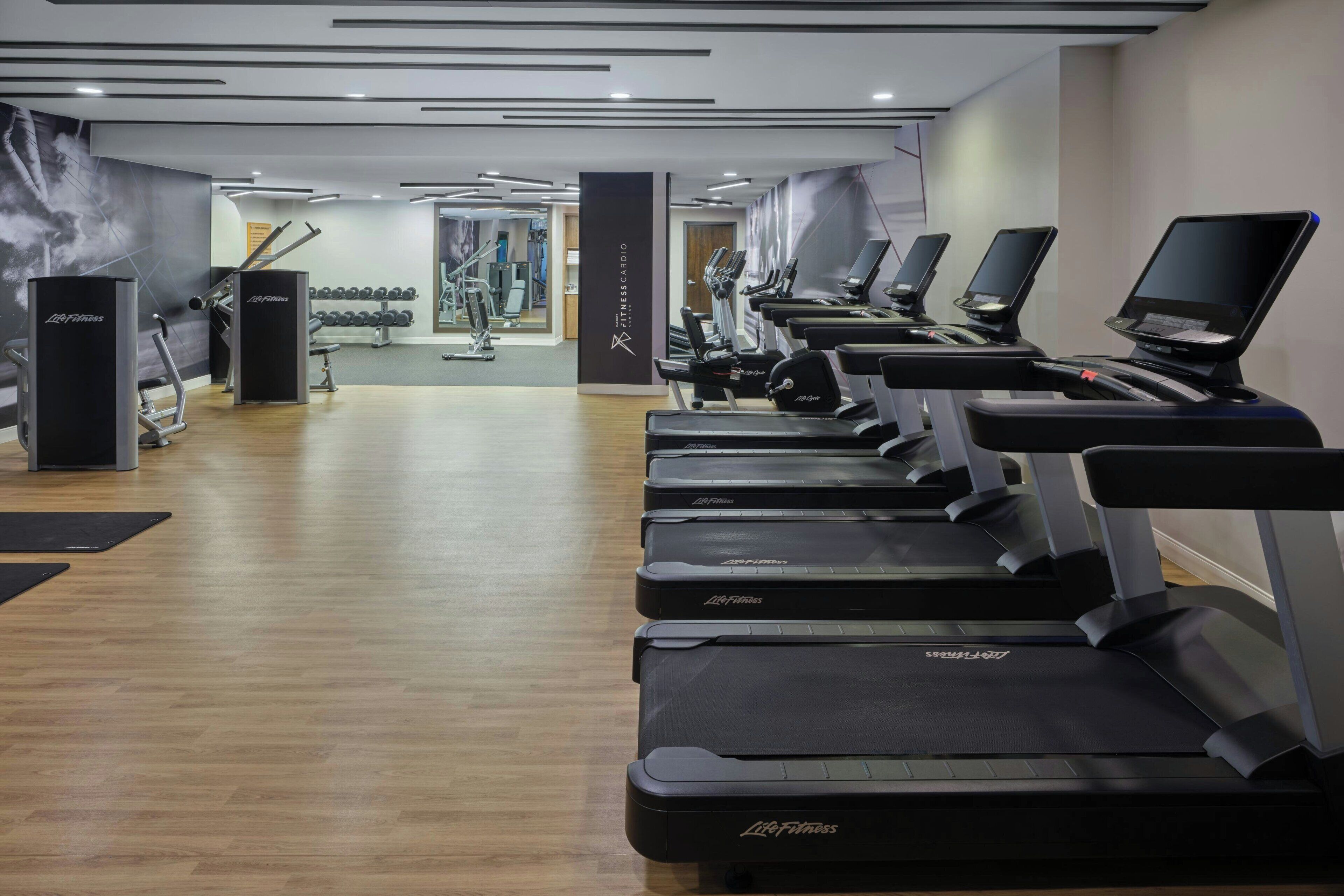 A gym with treadmills, weights, and a mirrored wall.