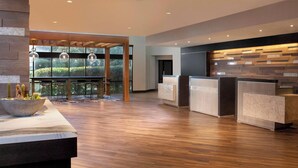 A modern reception area with wooden flooring, a reception desk, and a glass partition.