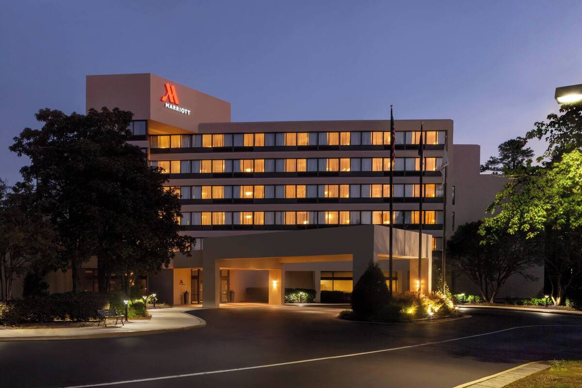 A multi-story hotel with a prominent 'Marriott' sign, a well-lit entrance, and a landscaped driveway.