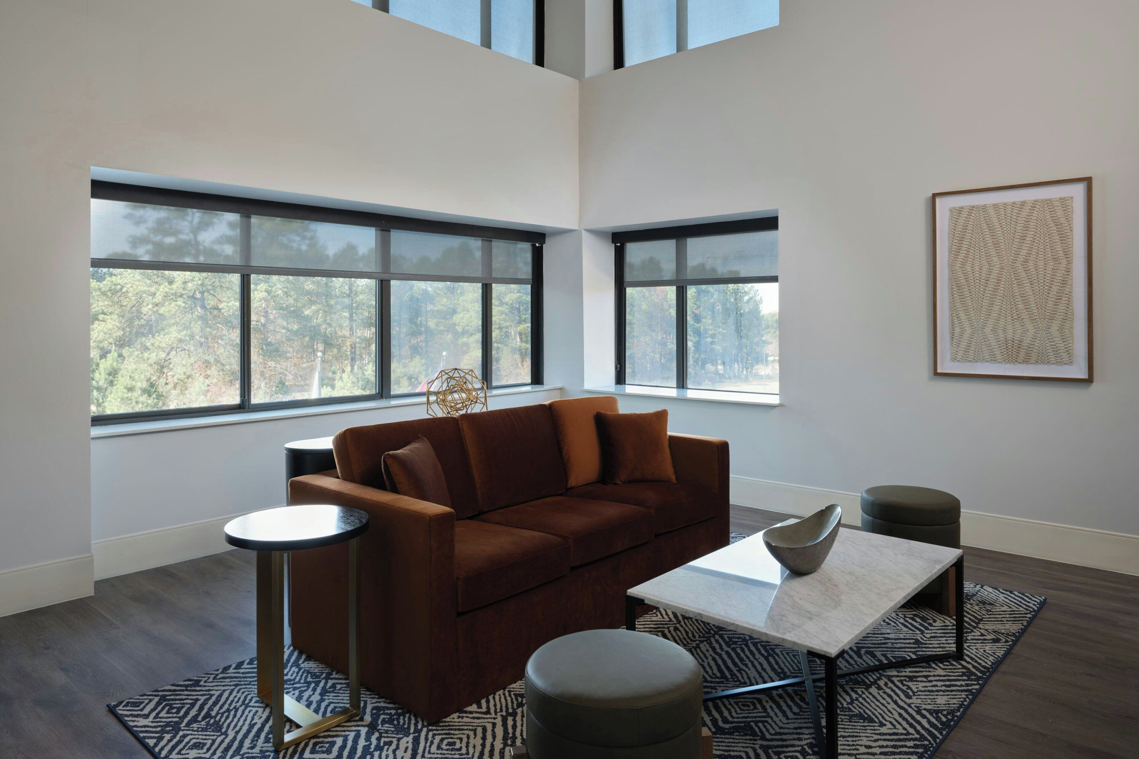 Un salon moderne avec un canapé marron, une table basse ronde et un tapis à motifs.