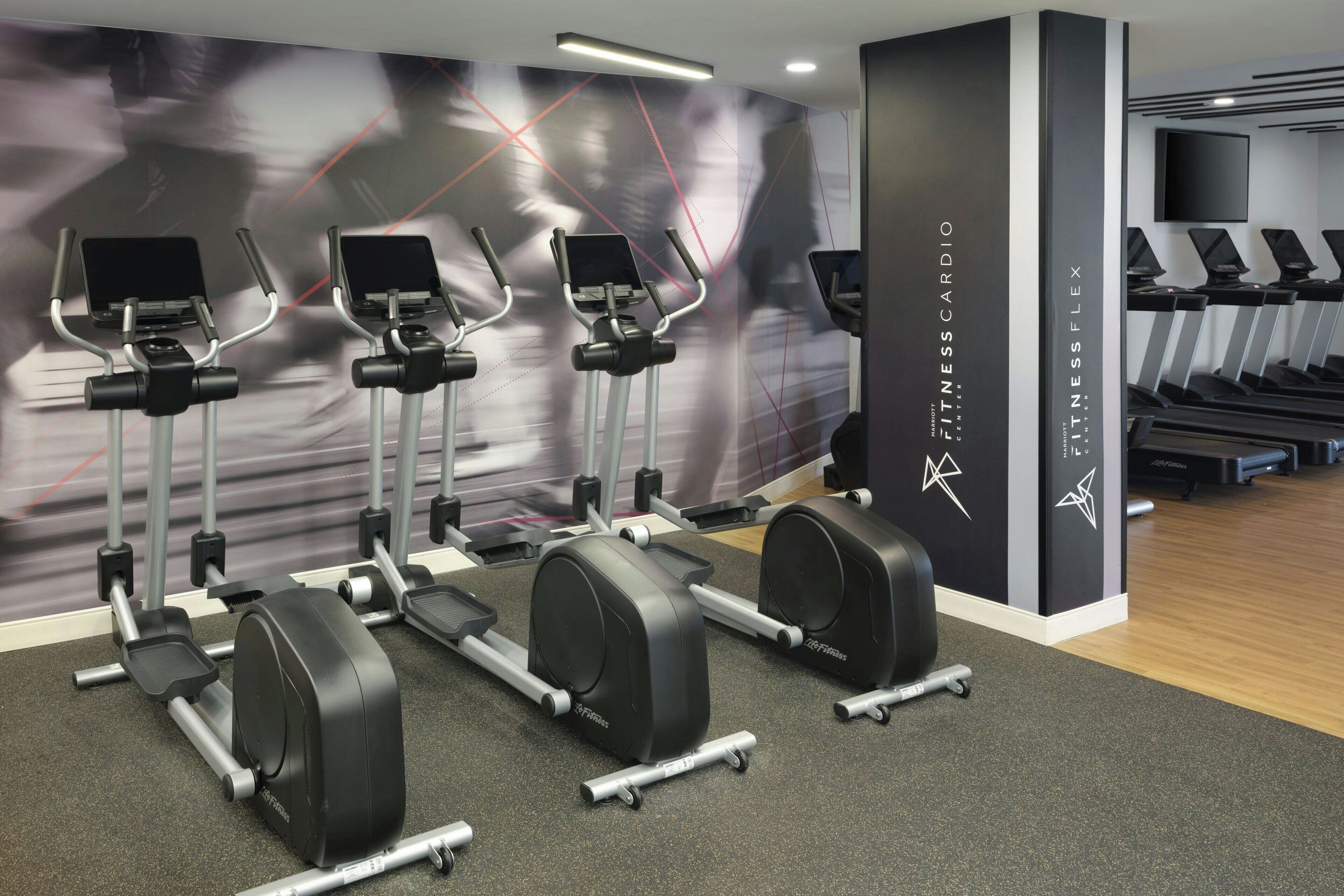 A gym with stationary bikes, treadmills, and a wall with a fitness theme.