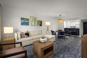 A modern living room with a sofa, coffee table, and chairs, a dining area with a table and chairs, and a kitchen in the background. - Saddlebrook Resort (Wesley Chapel)