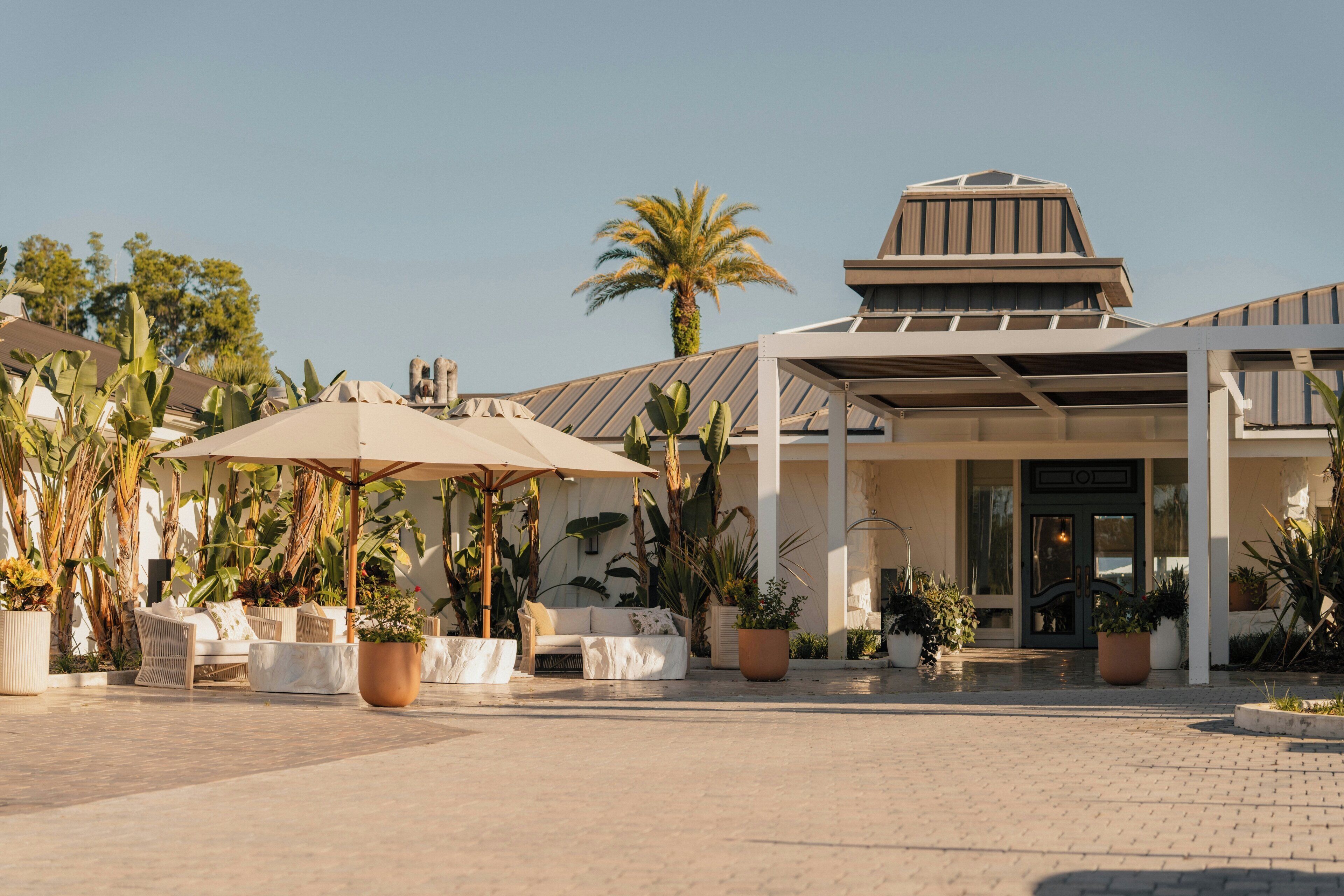 L’entrée d’un hôtel avec un patio couvert, des sièges en plein air et des plantes en pot.