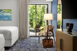 Habitación de hotel con cama, una silla, una mesa, una lámpara y vistas a zonas verdes.