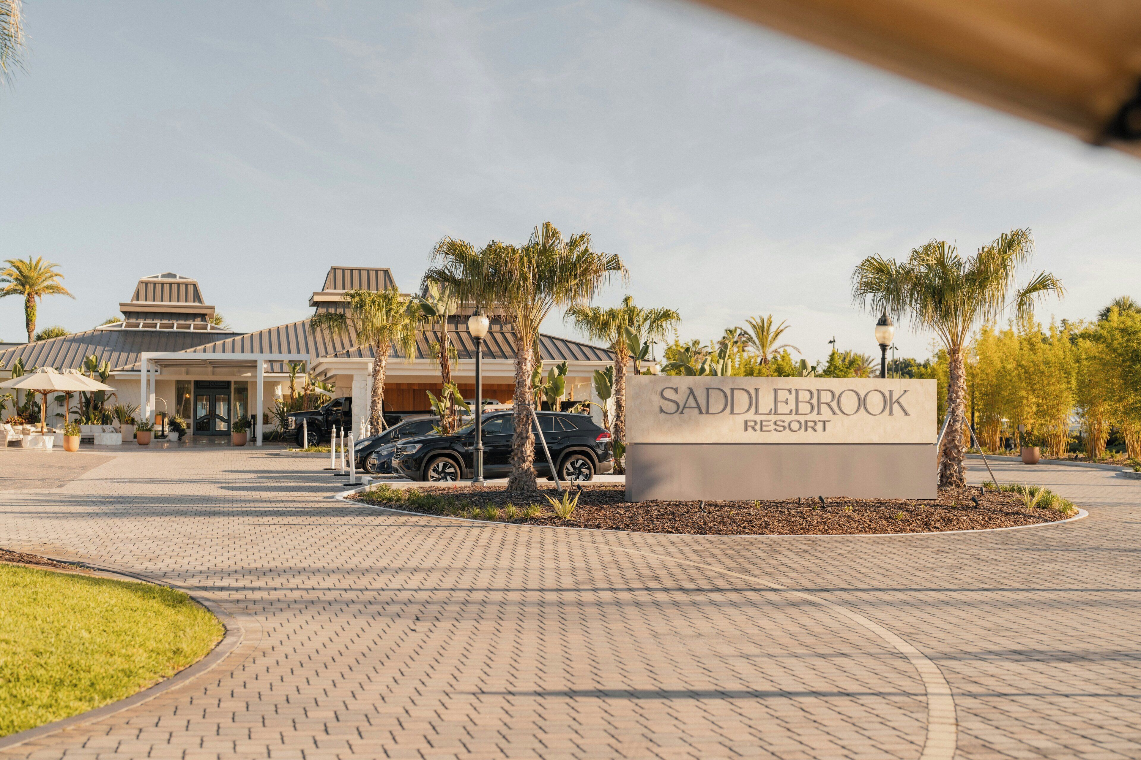 Une allée dallée mène à l’entrée, où se trouve un panneau indiquant le complexe hôtelier Saddlebrook Resort.