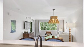 Une chambre d’hôtel moderne dotée d’une grande fenêtre, d’un coin repas et d’une salle de bain avec un lavabo.
