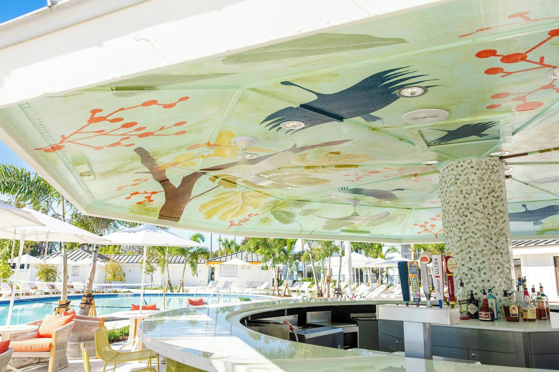 Ein Barbereich am Pool mit Deckenmalerei, einem Schwimmbecken und Liegestühlen.