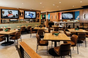 A restaurant with multiple tables and booths, sports-themed decor, and televisions displaying sports content. - Saddlebrook Resort (Wesley Chapel)