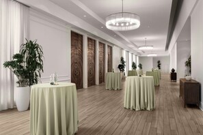 A hotel room with a long corridor, multiple round tables with green tablecloths, and a modern chandelier. - Saddlebrook Resort (Wesley Chapel)