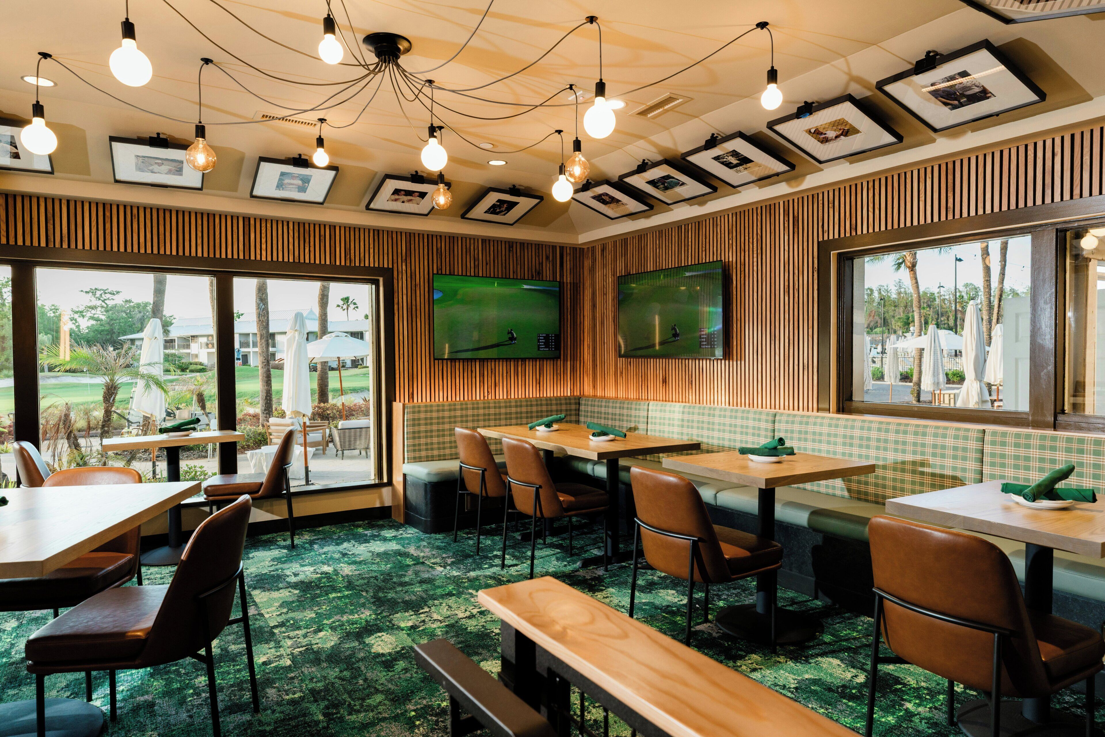 A restaurant with wooden paneling, green checkered booths, and a large TV screen.