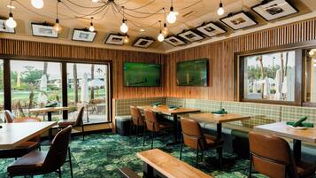 A restaurant with wooden paneling, green checkered booths, and a large TV screen.