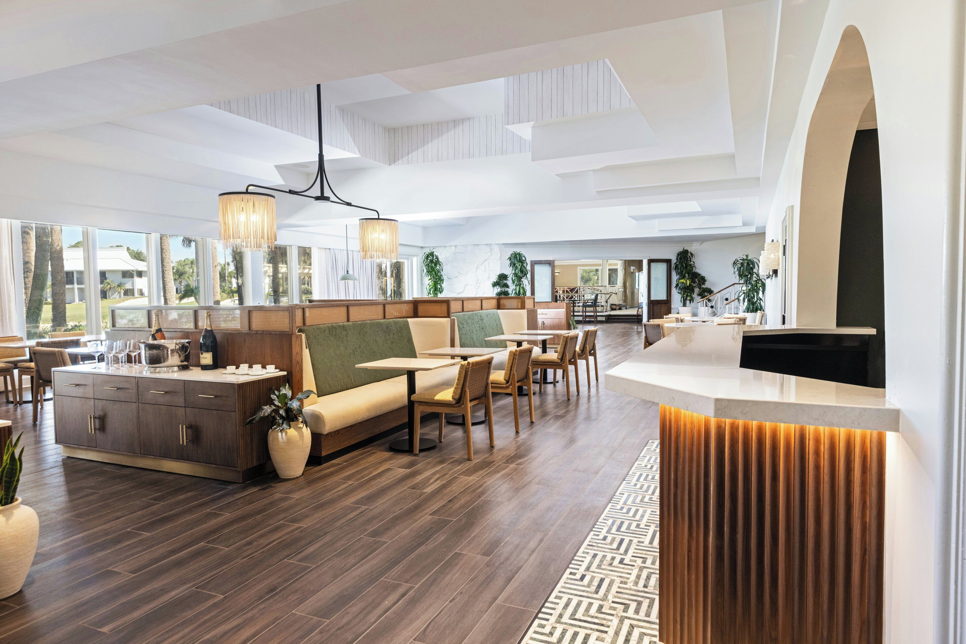 En rymlig hotellobby med en central sittgrupp, en receptionsdisk och stora fönster som erbjuder utsikt över omgivningarna.