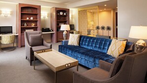 Un salon moderne avec un canapé bleu, un fauteuil marron, une table basse en bois et un téléviseur posé sur un meuble.