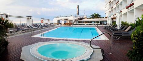 A pool area with sun loungers, a hot tub, and a lifebuoy.