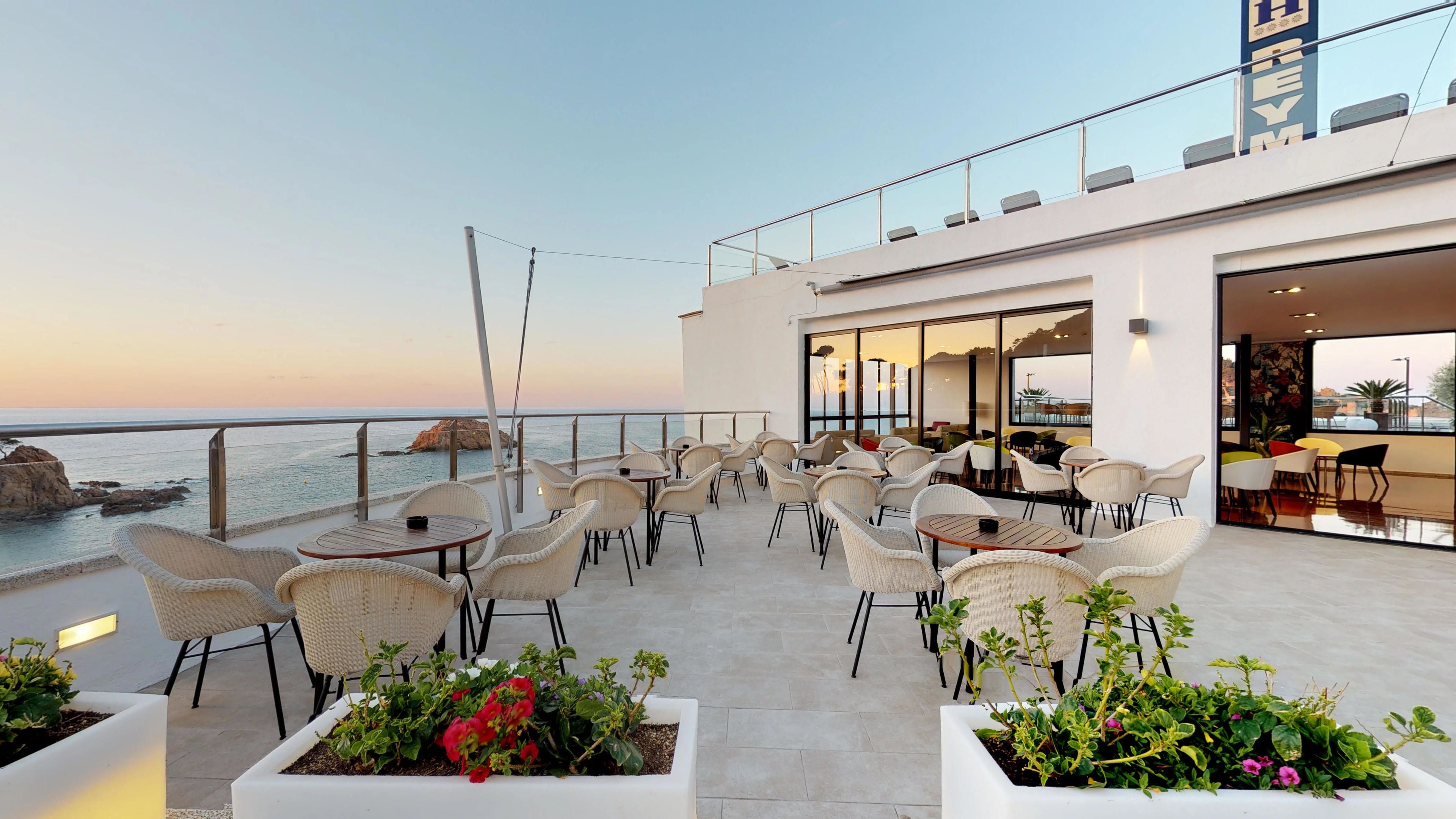 Une terrasse sur le toit, avec des sièges en plein air et une vue sur la mer.