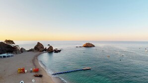 A beach with rocky formations, a pier, and boats. - Gran Hotel Reymar (Tossa de Mar)