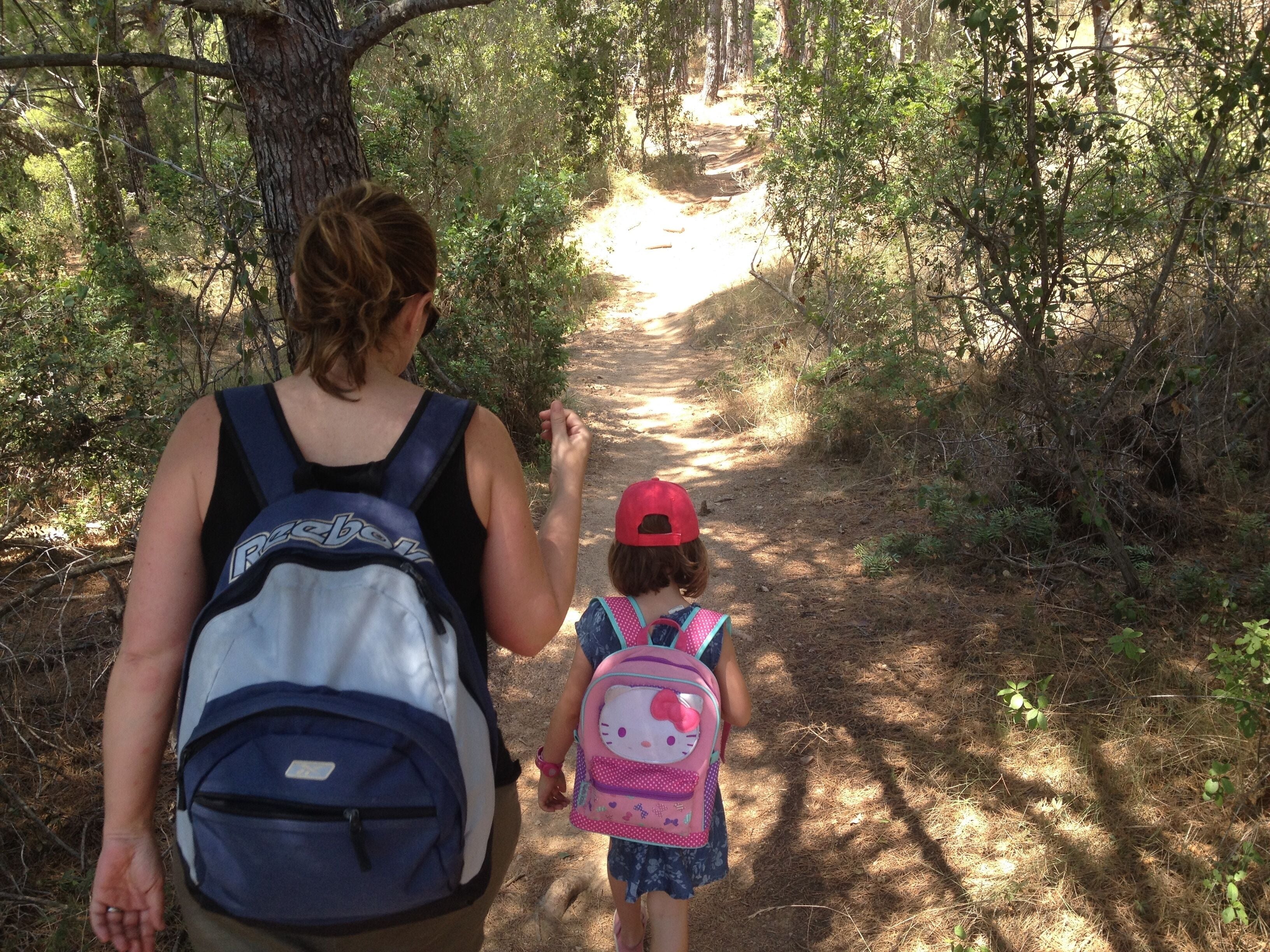 Una mujer y un niño caminando por un sendero en el bosque.