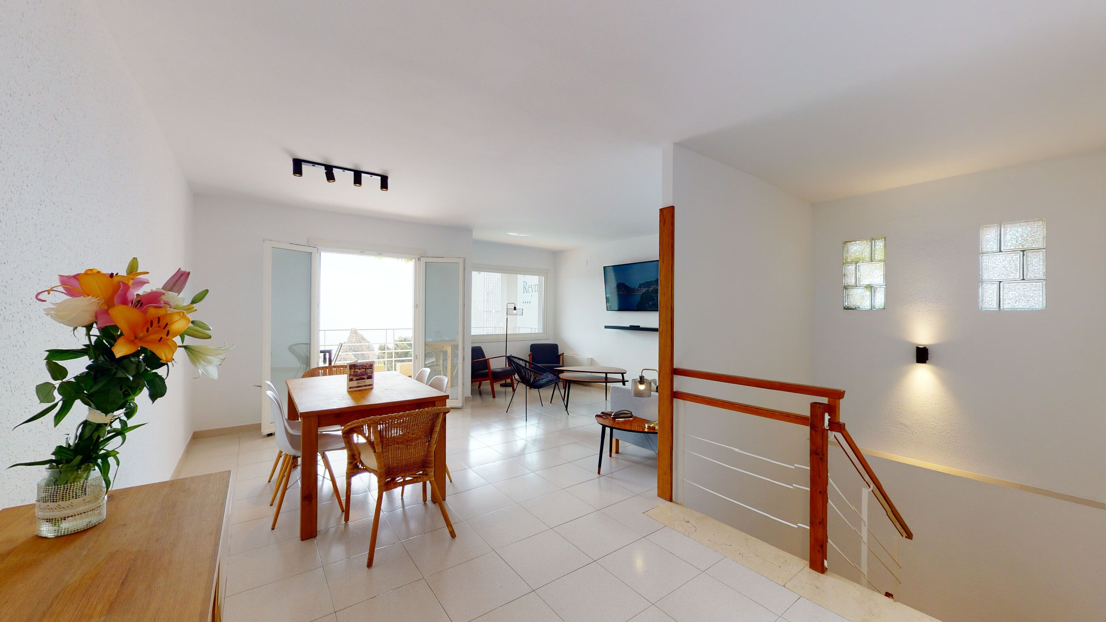 Ein modernes Wohnzimmer mit Essbereich, einer Treppe und einem Balkon.