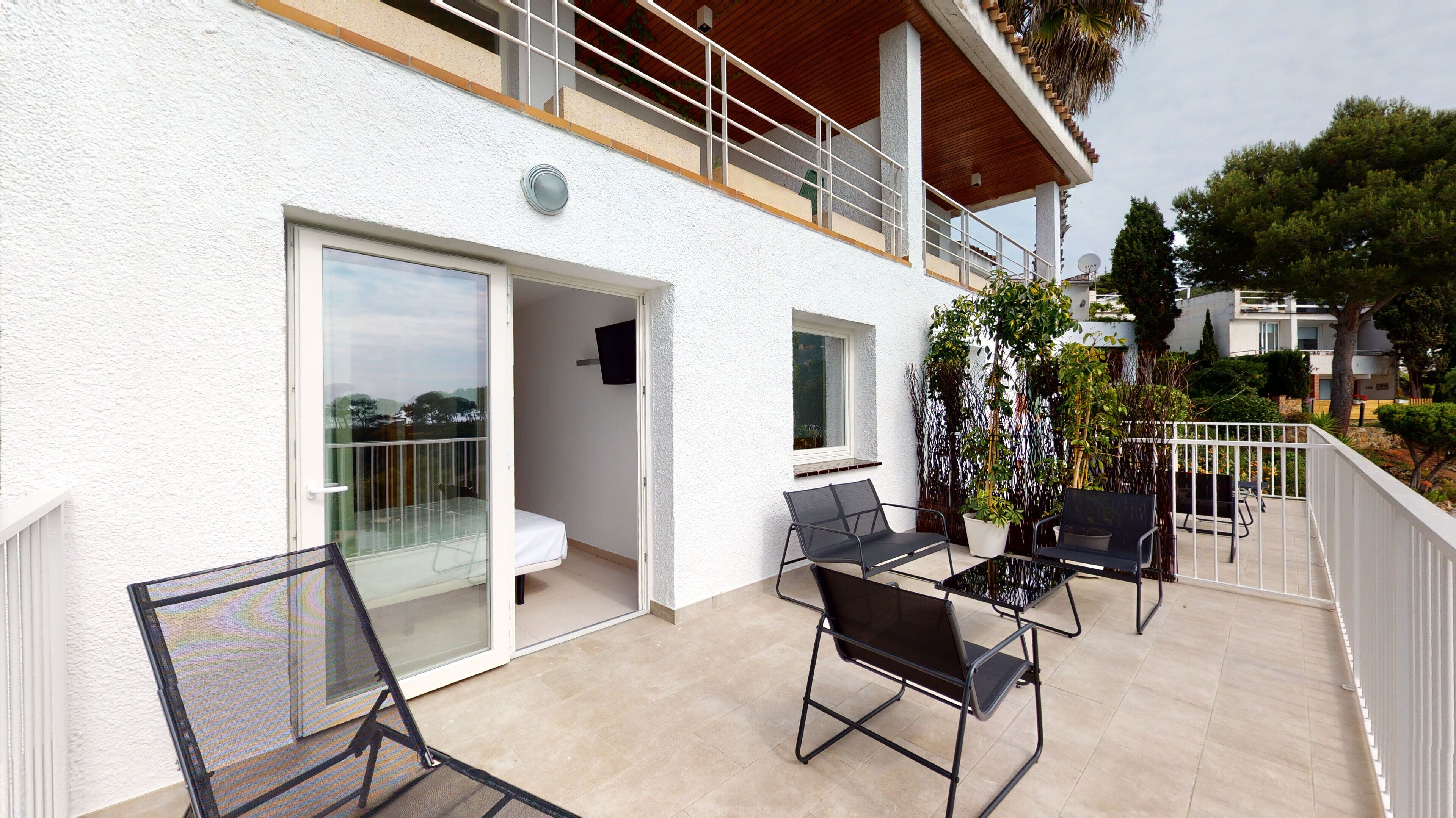 A balcony with outdoor furniture, a sliding glass door, and a view of the surrounding area.