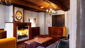 A cozy room with a fireplace, a wooden ceiling, a large mirror, and a comfortable seating area.