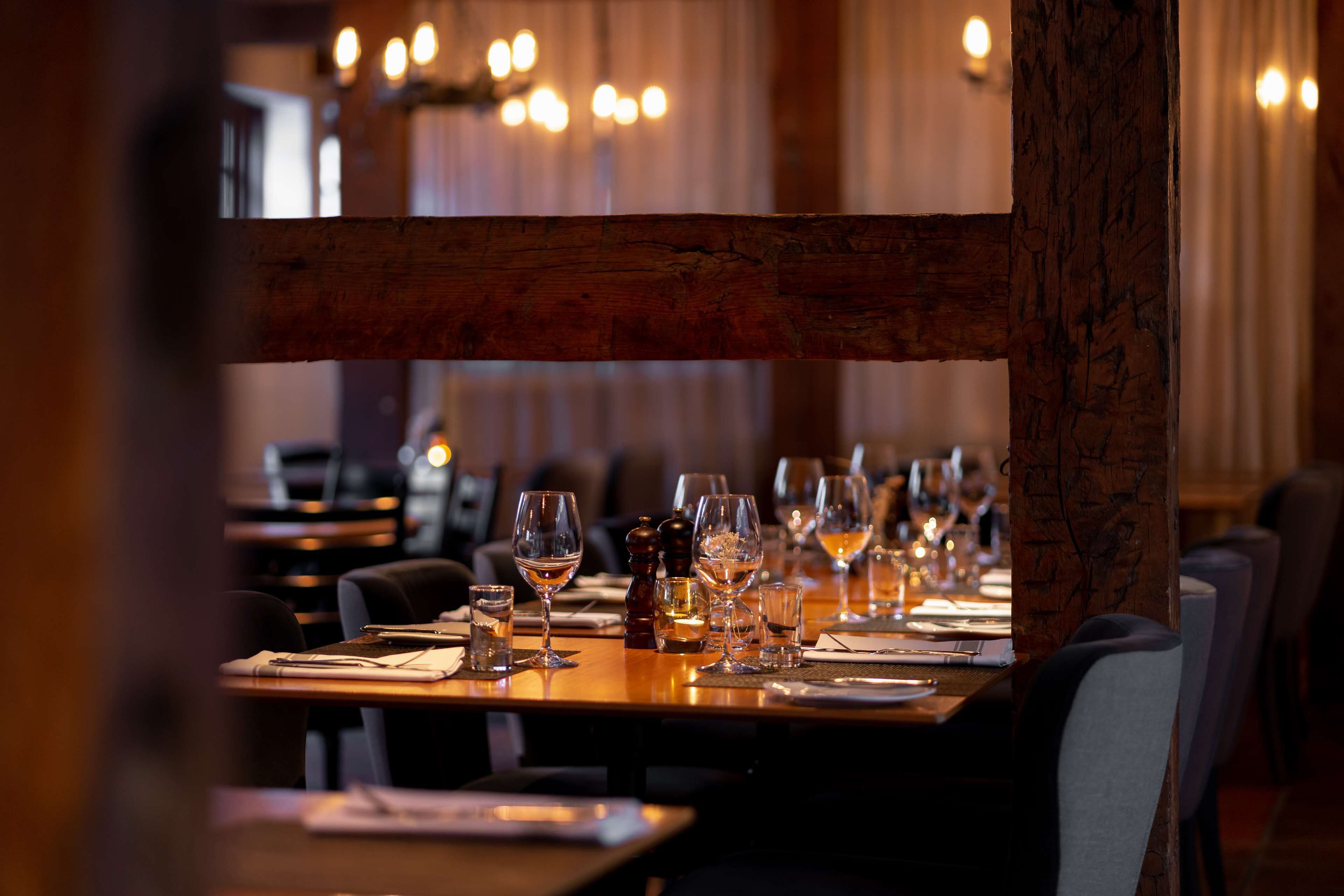 Un restaurante con mesas dispuestas para comer, con vigas de madera y un ambiente cálido.