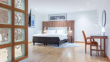 A modern bedroom with a bed, bedside tables, a desk, and a chair.