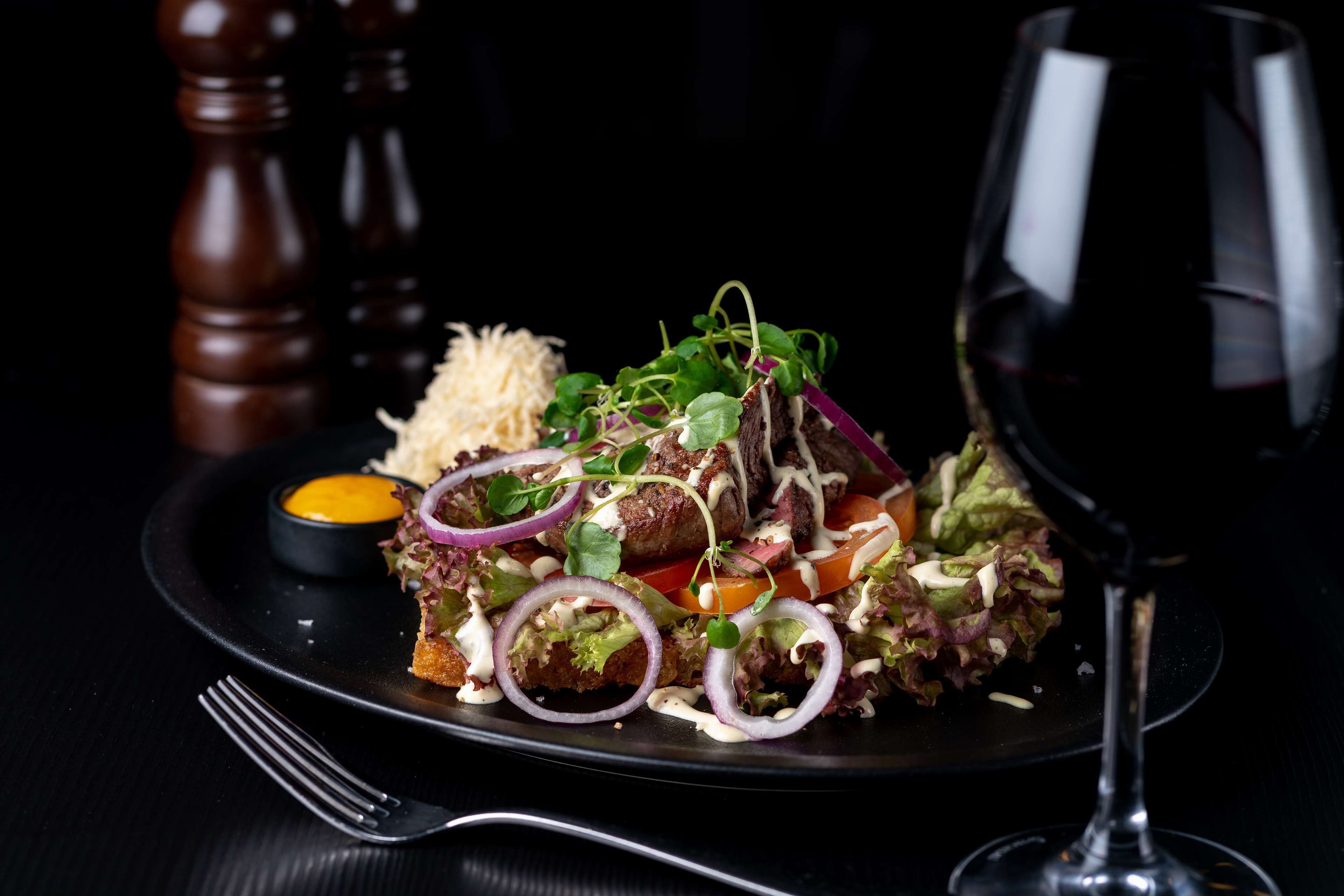 A plate of food with a glass of red wine.