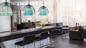 A modern hotel lobby with a central island, seating area, and large windows.