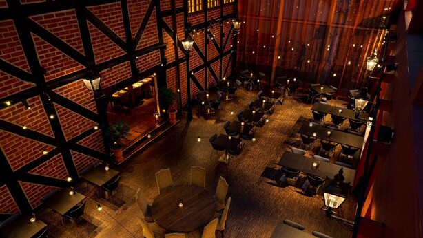 A spacious indoor dining area with multiple tables and chairs, brick walls, and hanging lanterns.