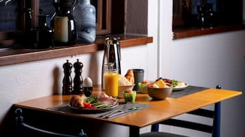 Una mesa de desayuno con croissants, huevos y un vaso de jugo de naranja.