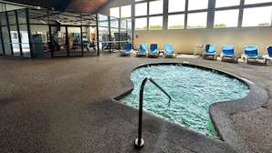 An indoor swimming pool with a diving board, surrounded by blue chairs and a glass enclosure with arcade games. - Cape Cod Irish Village (Hyannis)