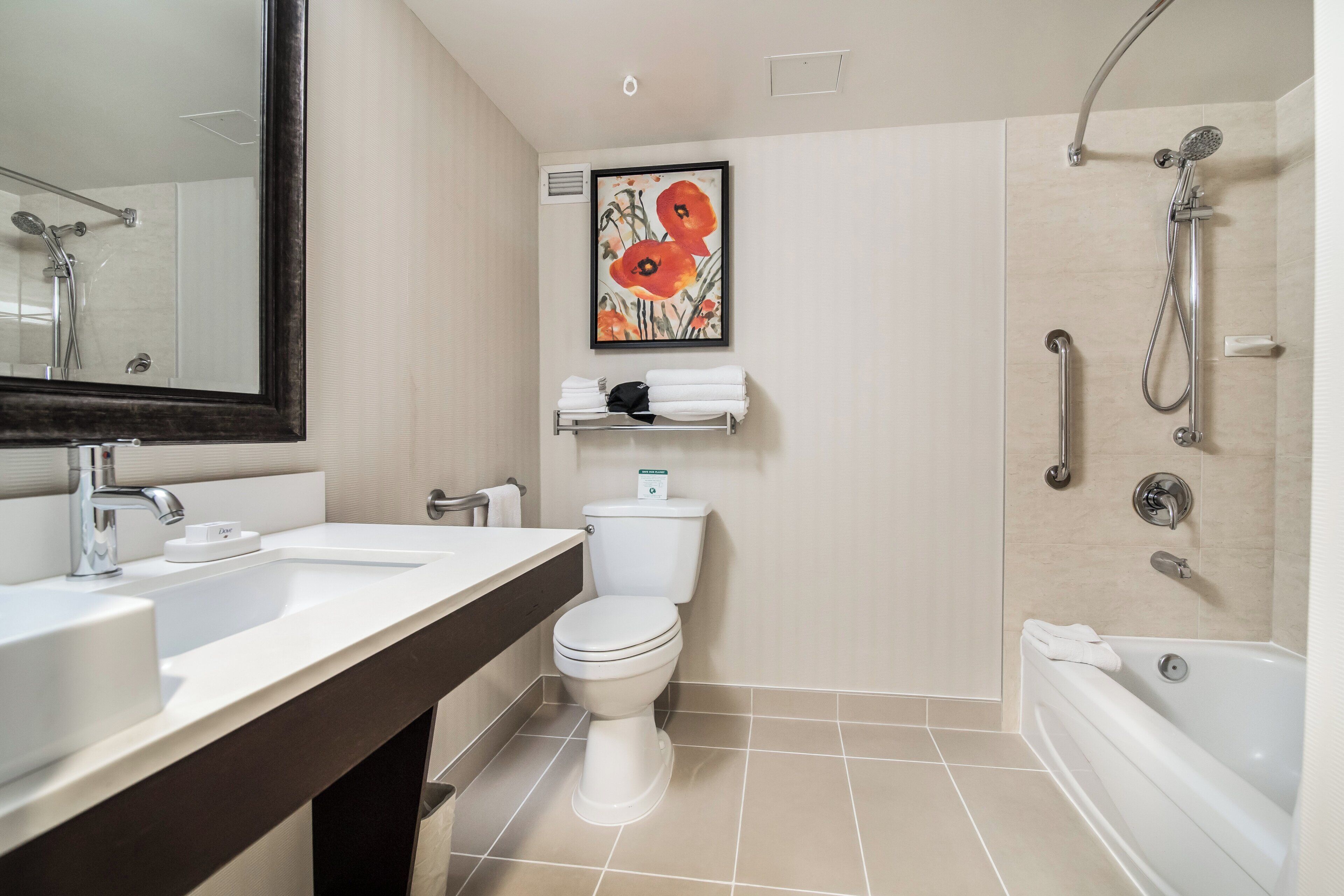 A modern bathroom with a large mirror, two sinks, a toilet, a shower, and a towel rack.