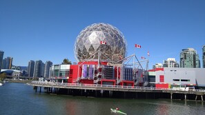 A waterfront view with a large spherical structure, a bridge, and modern buildings in the background.