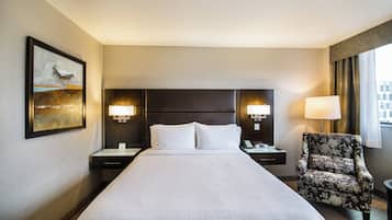A hotel room with a large bed, two bedside tables, a chair, and a painting on the wall.