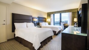 Una habitación de hotel con dos camas, un escritorio, una silla y un televisor.