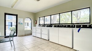 A laundry room with multiple washing machines, a bench, and a fire extinguisher. - Stayable Kissimmee West (Kissimmee)