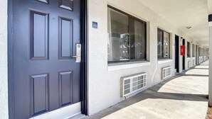 A building facade with a dark blue door, large windows, and a covered walkway. - Stayable Kissimmee West (Kissimmee)