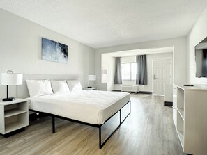 A modern hotel room with a large bed, bedside tables, a desk, and a television. - Stayable Kissimmee West (Kissimmee)