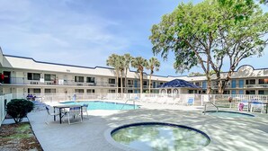 A hotel with a swimming pool, outdoor seating, and a fenced deck area. - Stayable Kissimmee West (Kissimmee)