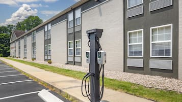 A parking lot with a row of buildings, a paved walkway, and a charging station.