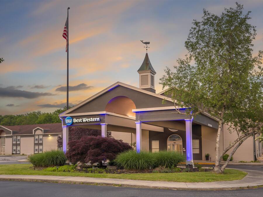 A Western Inn with a covered outdoor area, a flagpole with an American flag, and a church steeple in the background.
