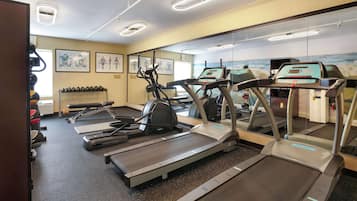 Un gimnasio con cintas de correr, elípticas y equipo de levantamiento de pesas.