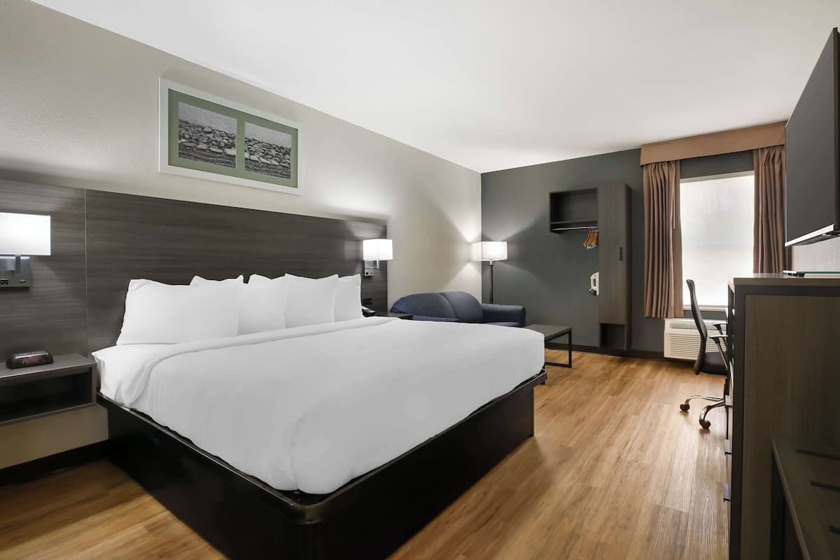 A modern hotel room with a large bed, bedside tables, a desk, and a chair.