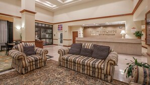 A lobby with two sofas, a reception desk, and a patterned rug. - Hawthorn Suites by Wyndham Midwest City Tinker AFB (Midwest City)