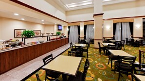 A hotel dining area with a buffet, multiple tables, chairs, and a television. - Hawthorn Suites by Wyndham Midwest City Tinker AFB (Midwest City)