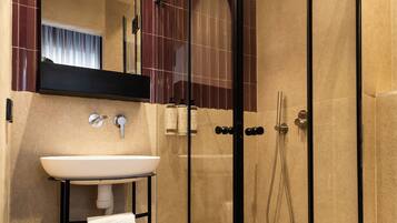 A modern bathroom with a glass-enclosed shower, a sink with a towel rack, and a mirror above the sink.