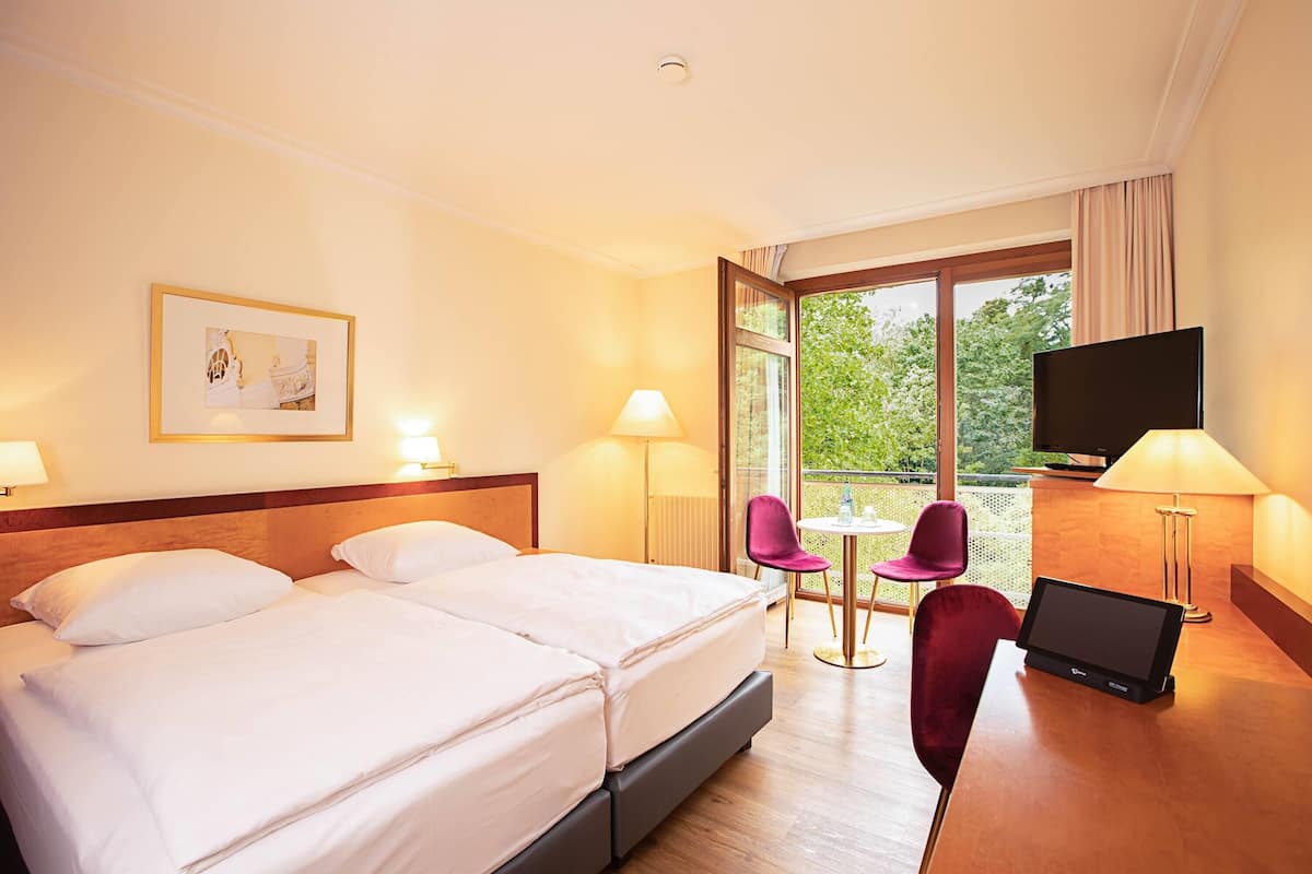 Une chambre d’hôtel avec un lit, un bureau avec un ordinateur portable, une télévision et un balcon avec vue.