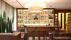 Un restaurant doté d’un bar à vin, de meubles en bois et d’un grand luminaire suspendu.