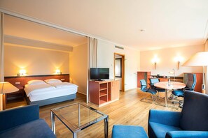 Ein Hotelzimmer mit Bett, Fernseher, Schreibtisch, Stuhl und Tisch.