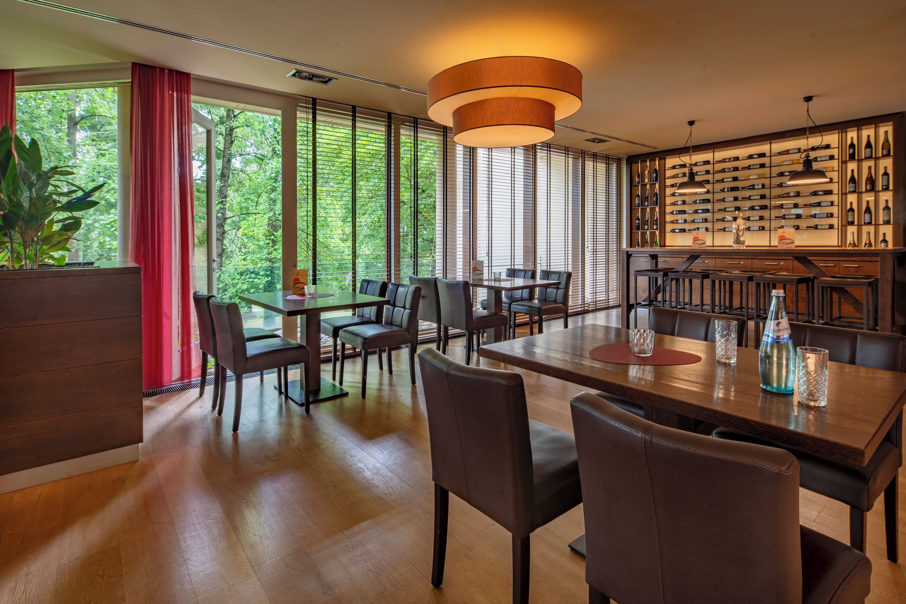 Un comedor moderno con suelo de madera, ventanas amplias y una pared llena de botellas de vino.